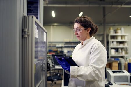 Lab assistant in white coat records results in laboratoryの写真素材