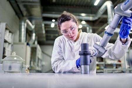 Woman lab technician in blue rubber gloves with 3D printer,