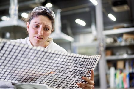 Close up young woman lab technician sitting at table with carbon meshの写真素材