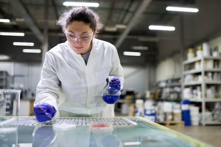 Laboratory woman with flask with blue liquid in her hands checks qualityの写真素材