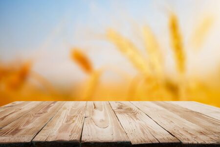 Wooden surface on blurred background of wheat, blue sky, close-up.の写真素材