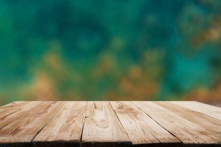 Wooden surface on blurry green and brown background.