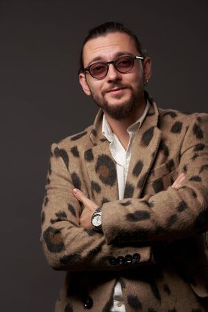 Man in sunglasses in jacket with arms crossed on brown backgroundの写真素材