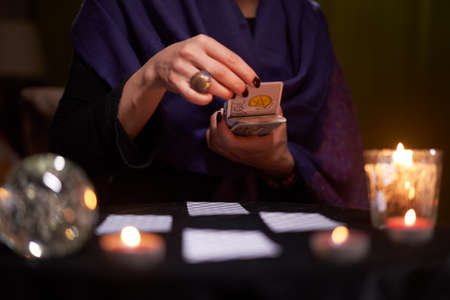 12.02.20. Moscow, Russia. Fortuneteller divines on cards at table with candles in dark room