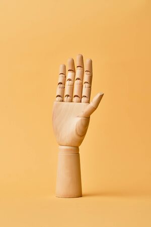 Wooden hand isolated on orange backgroundの写真素材