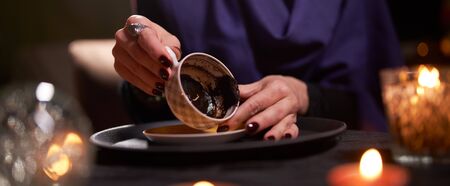 Woman fortune teller divines on coffee grounds at table with ball of predictionsの写真素材