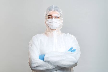 Man in protective suit, medical mask, goggles with arms crossed. Isolated in studioの写真素材