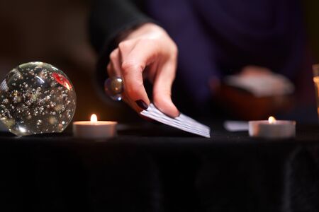 Fortuneteller female divines on cards sitting at table with candlesの写真素材