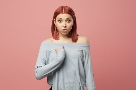 Serious woman pointing her finger at herself while standing in studioの写真素材