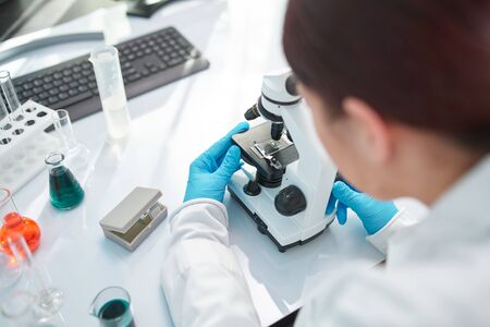 Female laboratory assistant looking through microscope in laboratory, closeup.の写真素材
