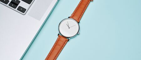 Wristwatch, laptop, pot of cactus on an empty blue background, top view. Business concept