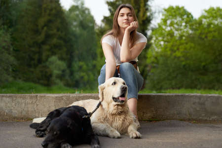 Pensive woman squatting next to dog on summer day.