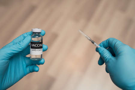 Doctor hands in protective gloves hold vaccive and syringeの写真素材