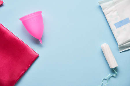 Pink menstrual cup and variuos of tampons on blue backgroundの写真素材
