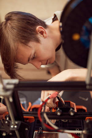 Young male technician fixing 3D printerの写真素材
