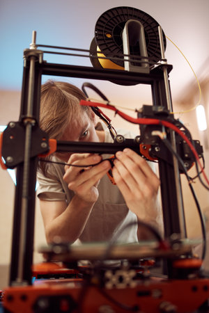 Young male technician fixing 3D printerの写真素材