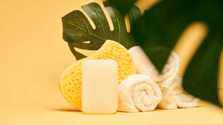 Soap, towels and body sponge over yellow background