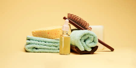 Bath and spa accessories. Soap, towels, serum and body sponge over yellow background