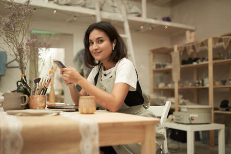 Female potter with smartphone looking at camera