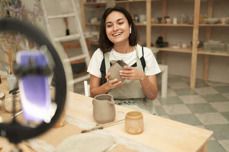 Delighted female artisan shooting video for pottery blogの写真素材