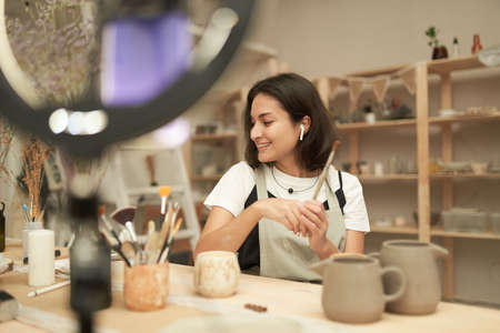 Cheerful blogger sitting at table in pottery