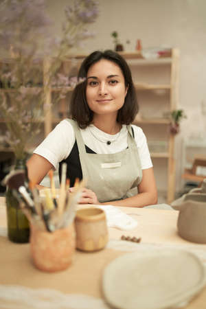 Female potter sitting at workbench