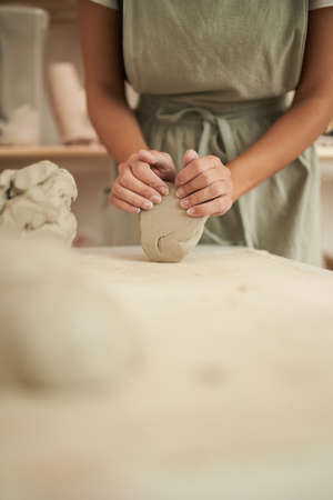 Crop female potter kneading clayの写真素材