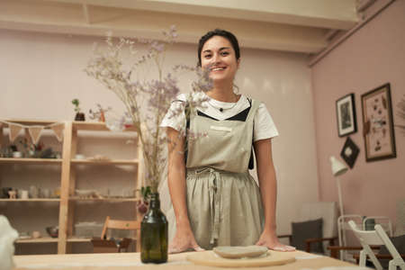 Smiling craftswoman working with clay in studioの写真素材
