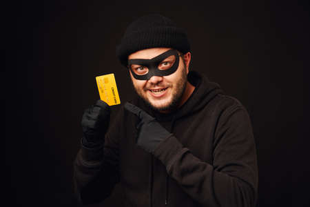 Funny thief holding credit cardの写真素材