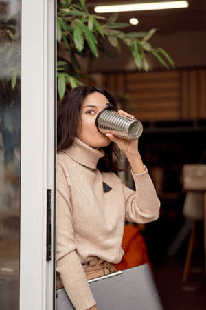 Female freelancer drinking coffee in doorway
