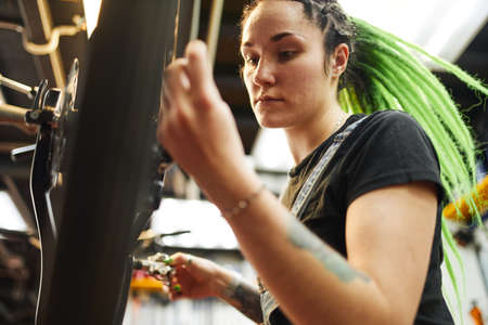 Female master fixing bicycle in workshopの写真素材