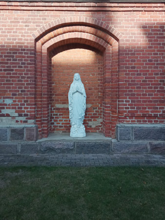 White Virgin Mary statue against red brick wallの写真素材