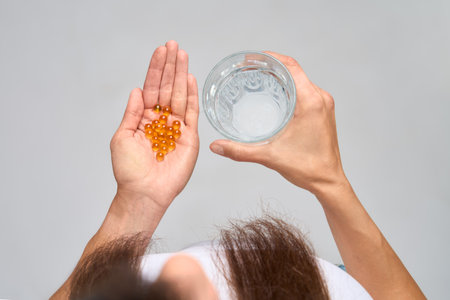 Top view of woman holding glass of water and omega-3 capsulesの写真素材
