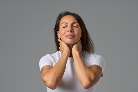 Calm woman closing eyes and holding neck gently expressing relief and relaxation