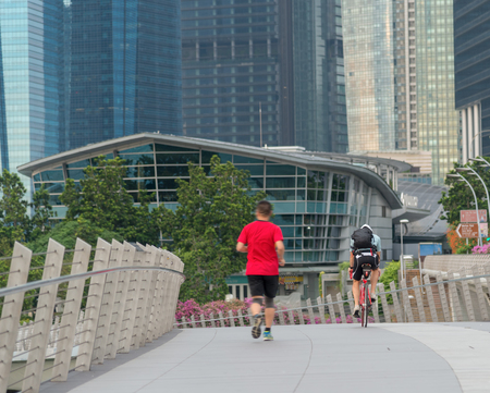 Runners and cyclists exercise in the morning along the bridge near Marina Bay in Singaporeの写真素材