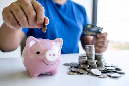 Man putting coins to planning growing saving to strategy with piggy bank for future plan fund of travel , education, home and retirement.の写真素材