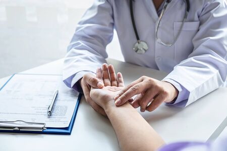 Doctor checking measuring pressure on patient's hand pulse by hands, Medical and healthcare concept.