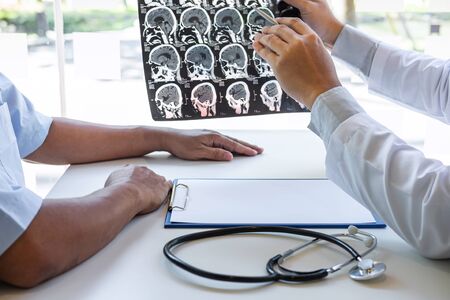Doctor holding and looking at x-ray film examining at brain by ct scan of patient and analyze result...