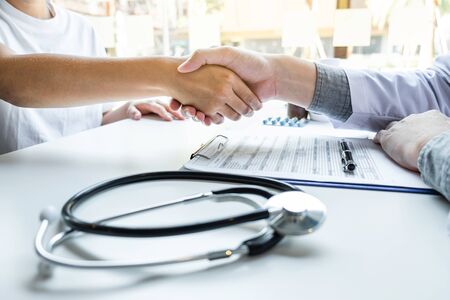 Doctor and patient shaking hands after a good and successful treatment in the hospital, healthcare and assistance concept.の写真素材