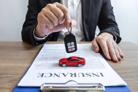 Car rental and Insurance concept, Young salesman receiving money and giving car's key to customer after sign agreement contract with approved good deal for rent or purchase.の写真素材