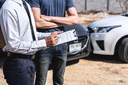 Insurance Agent and customer assessed negotiation, checking and signing on report claim form process after accident collision, Traffic Accident and insurance concept.の写真素材
