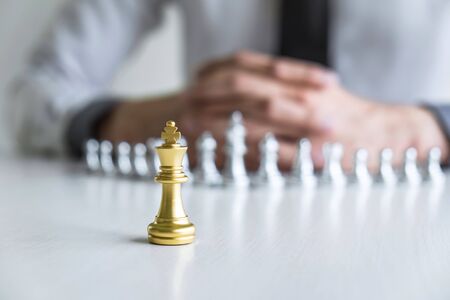 Gold and silver chess with player, Hands of businessman moving chess figure in competition to planning strategy to success play for win.の写真素材