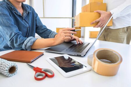 Young entrepreneur business owner work at home, small business startup receive order client and take note working with report and pack the product on purchase delivery online to sending destination.の写真素材
