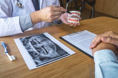Professional Dentist and patient discussing jaw and teeth the x-ray photograph during explaining the...