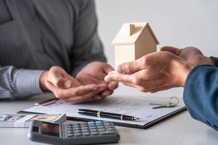 Real estate agent are presenting home loan and giving house to customer after signing contract to...
