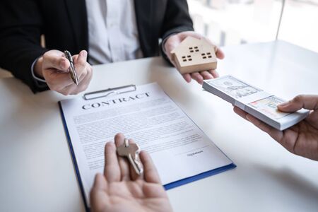 Real estate agent are presenting home loan and sending keys to customer after signing contract to...