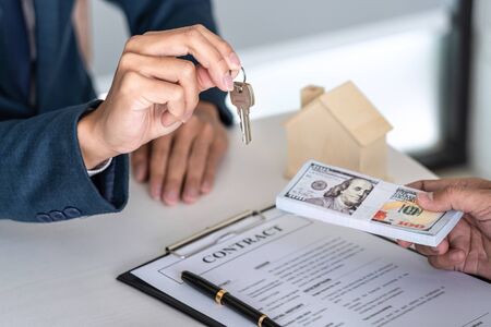 Real estate agent are presenting home loan and sending keys to customer after signing contract to...