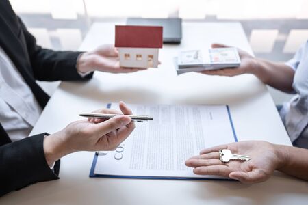 Real estate agent are presenting home loan and sending keys to customer after signing contract to...
