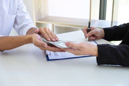 Businessman giving bribe money in the envelope of their partner to give success the deal contract in...