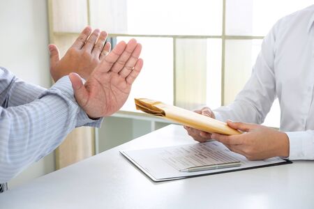 Businessman refusing receive bribe money in the envelope of their partner to give success the deal contract in a corruption scam, illegal, dishonest, bribery and corruption concept.の写真素材
